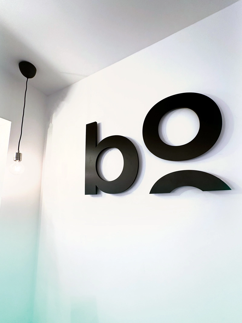 Gros plan sur le logo de bo école accroché au mur blanc.