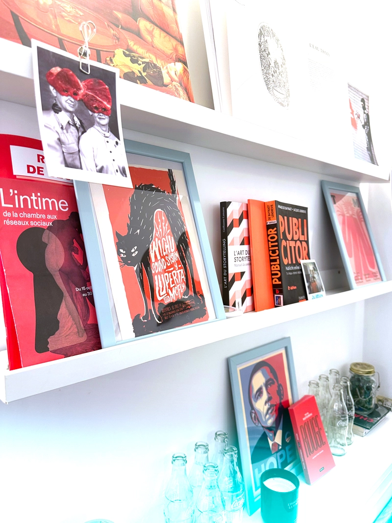Zoom sur les étagères de la salle rouge de bo école avec des livres et des affiches design.